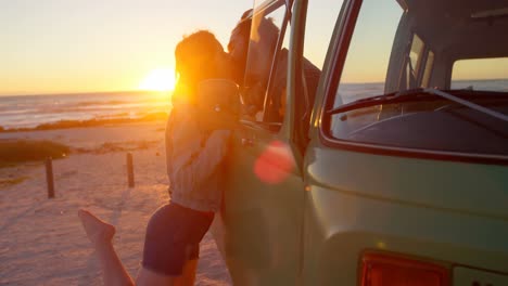 Romantic-young-couple-kissing-through-van-window-on-beach-4k