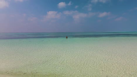 Ein-Mann-Steht-Im-Türkisfarbenen-Wasser-Vor-Einem-Stürmischen-Himmel