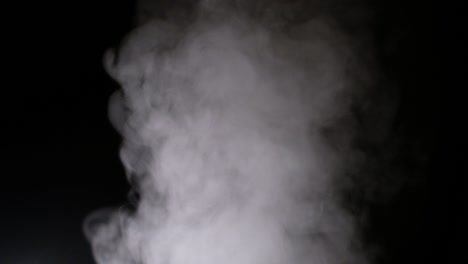 white steam spins and rises from the pan. white smoke rises from a large pot, which is located behind the frame. isolated seamless loop black background.