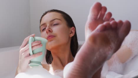 woman drinking coffee while relaxing in a bathtub