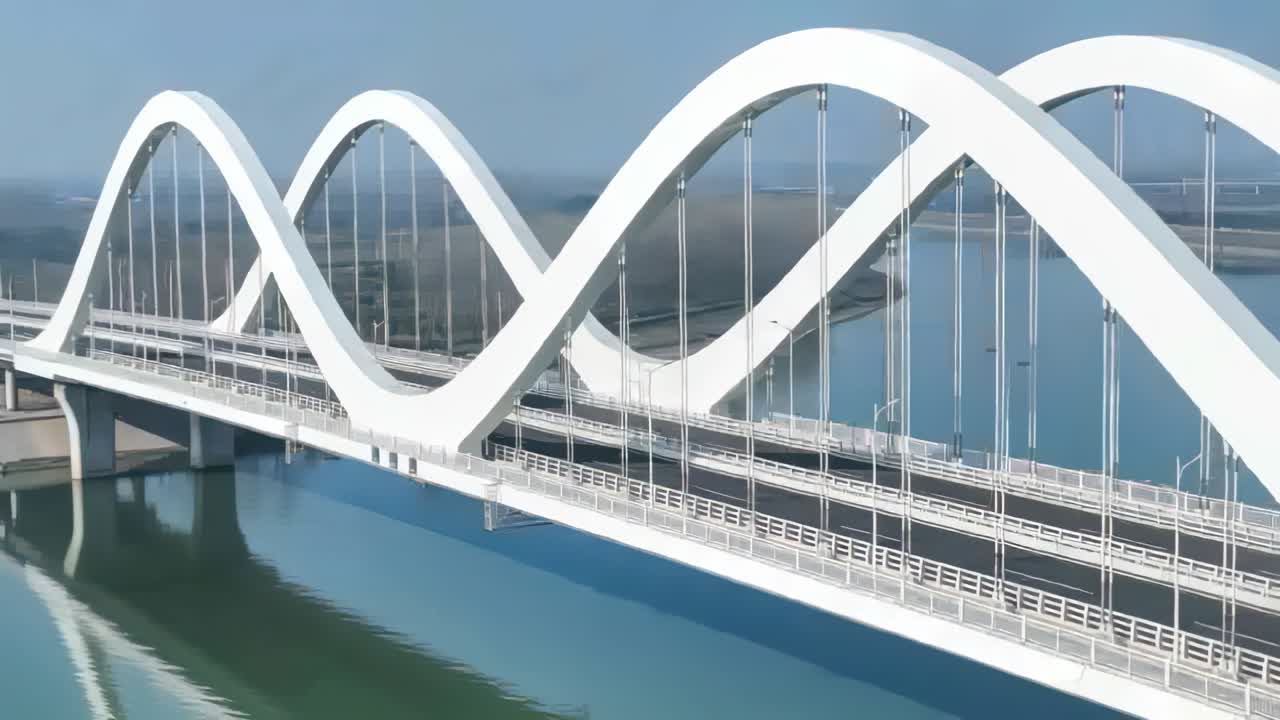 Panning drone camera revealing modern white arch bridge over river, showing cables and reflections