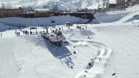 Vista-Aérea-Del-Ascensor-Del-Complejo-De-Nieve-Farellones-Repleto-De-Turistas,-Montañas-Al-Fondo