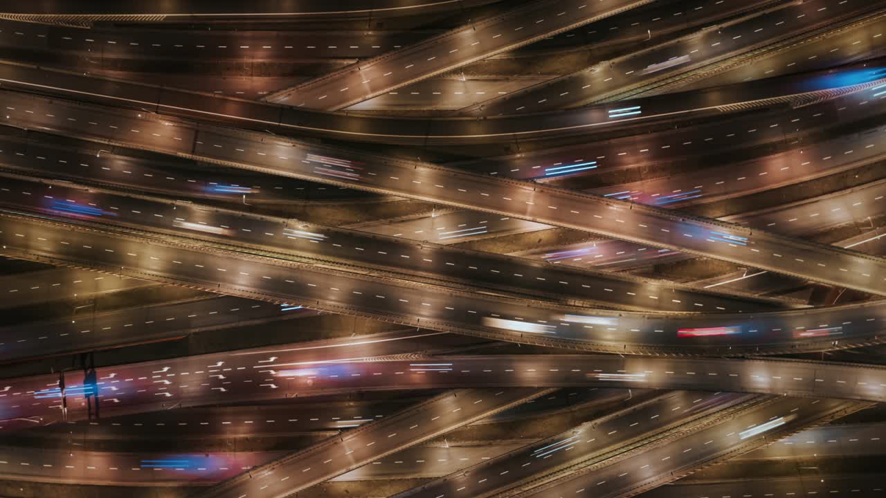 aerial time lapse atasco de tráfico carretera de intercambio de varios niveles por la noche, drone de arriba hacia abajo vista de muchas carreteras intersección en la ciudad de la noche. coches conduciendo busy intersección autopista, cruce de carreteras