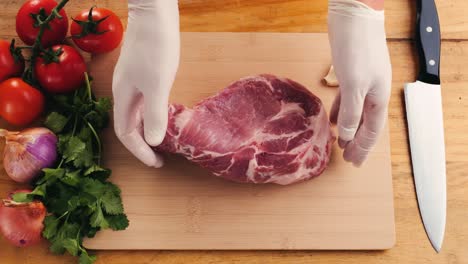 raw pork chop on a wooden cutting board with vegetables