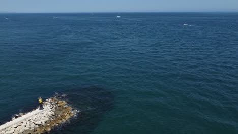 torre de señales de barco al final del rompeolas cerca del agua azul del océano, vista aérea