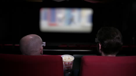 two men share popcorn in a film cinema theatre