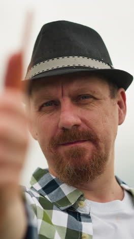 close-up of a sculptor in a checked shirt and hat, holding a brush with intense focus, against a blurred background