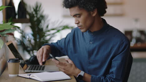 young mixed race businessman using smartphone browsing research information online writing creative ideas in journal diary brainstorming entrepreneur enjoying relaxed coffee shop cafe