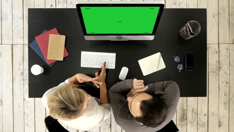 pareja de negocios hablando y viendo la imagen en la pantalla del monitor. pantalla verde muestra de maqueta