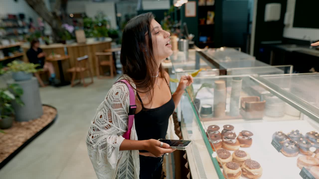 Una donna in un bar che guarda delle ciambelle