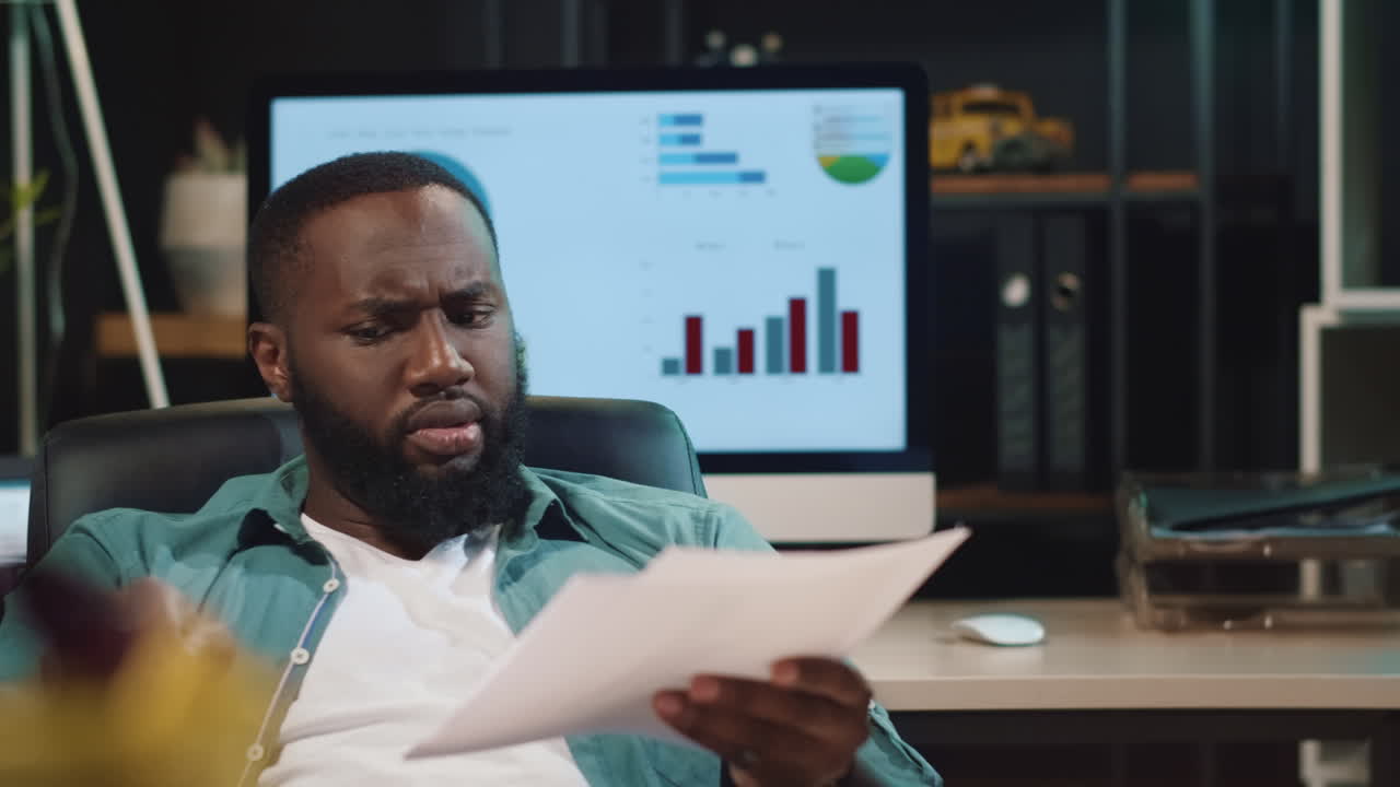 Closeup stressed african man looking papers in office. Afro guy checking data