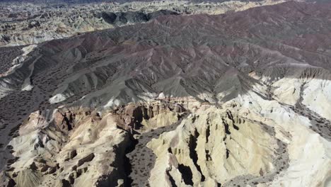 Aerial-rotates-over-rugged-eroded-clay-hillside-mountain-landscape