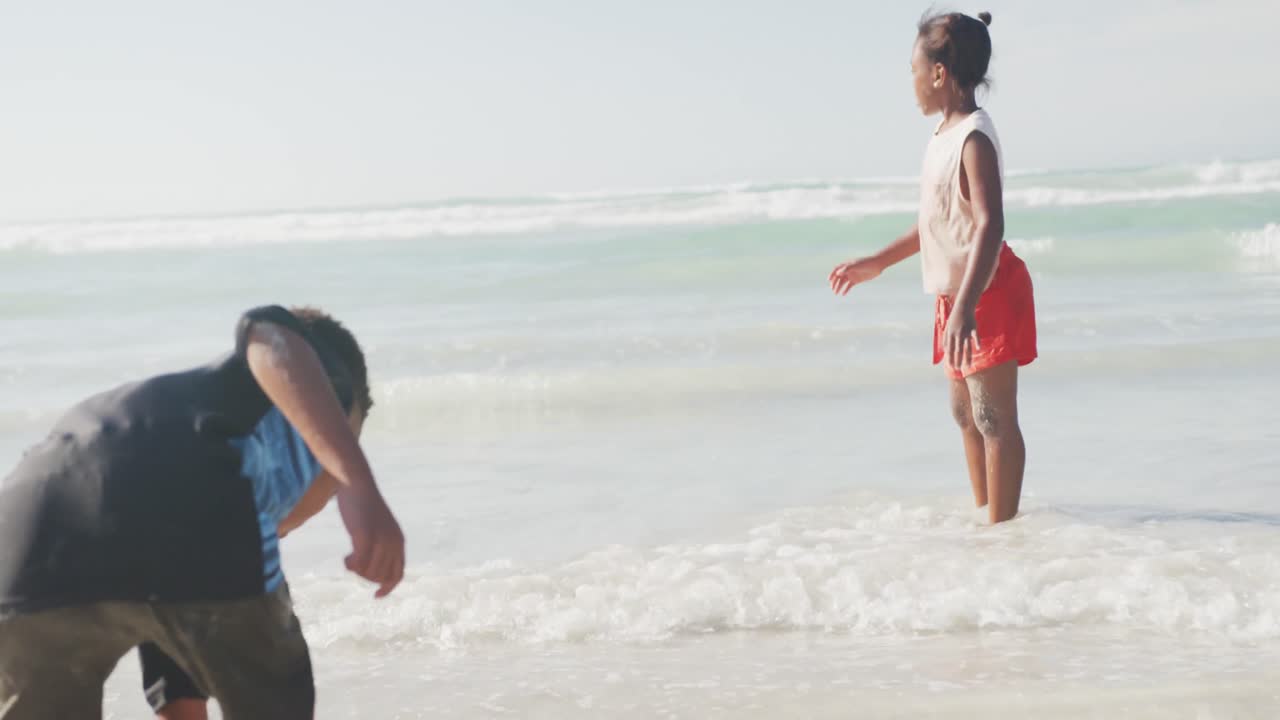 아프리카계 미국인 형제 자매가 해변에서 점프하고 즐기고 있습니다.