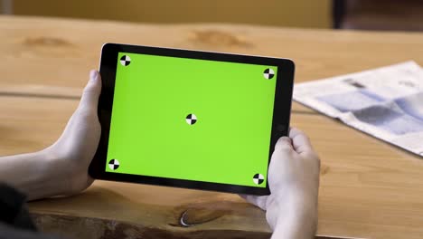 persona que sostiene una tableta con una pantalla verde