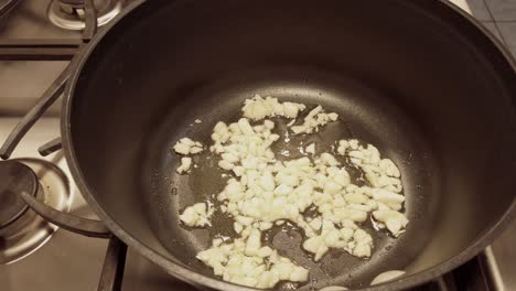 no person, non-stick pan saute garlic in olive oil, side profile shot.