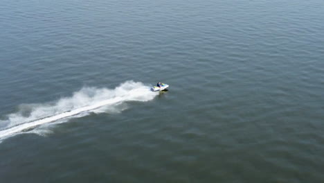 drone shot of man jet skiing on ocean in mississippi on clear sunny day
