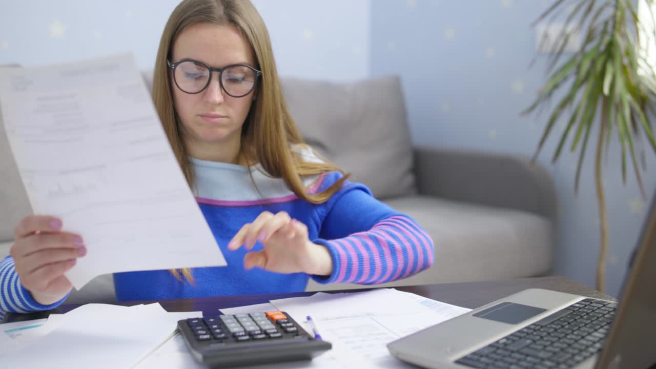 mujer usando calculadora para calcular facturas domésticas en el hogar, haciendo papeleo para pagar impuestos