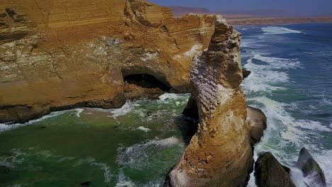 aerial shot over la catedral rock panning around viewing the cliffs with ocean waves in peru, south america