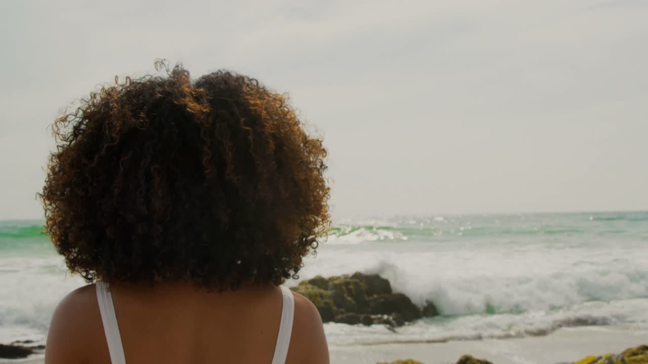 vista trasera de una mujer afroamericana de pie en la playa 4k