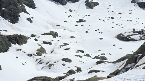 people freeriding down rocky slope of snowy mountain