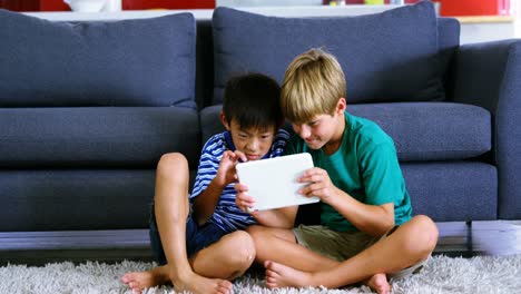 Siblings-using-digital-tablet-in-living-room