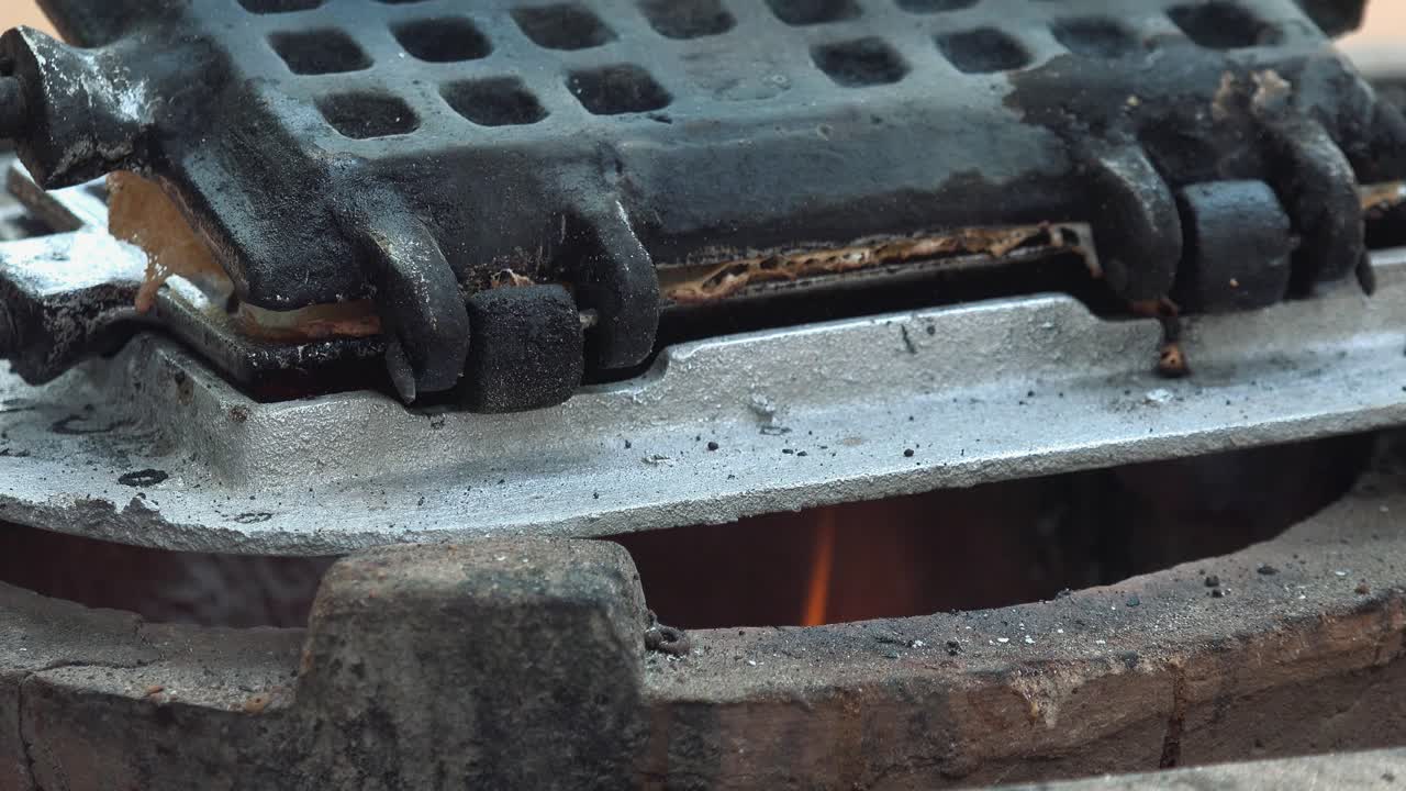Close Shot of a Waffle Iron Being Turned on the Fire