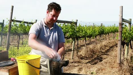 beekeeper preparing smoker for harvesting in apiary