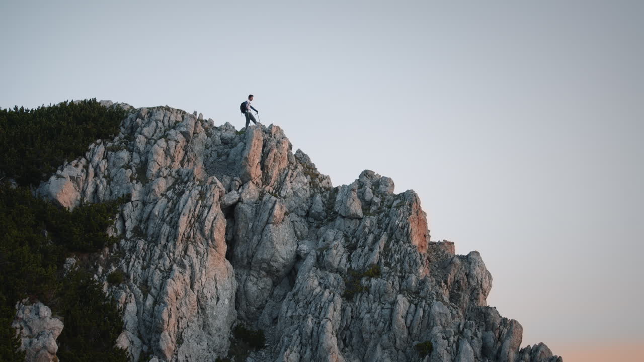 toma del excursionista parado al final de la cresta de la montaña en la peca de la montaña temprano en la mañana al amanecer