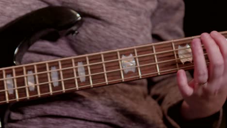 a-woman-playing-bass-guitar-against-a-black-backdrop