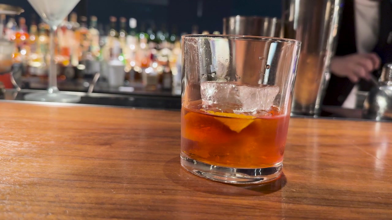 Cocktail Negroni con grande cubo di ghiaccio sul bancone del bar