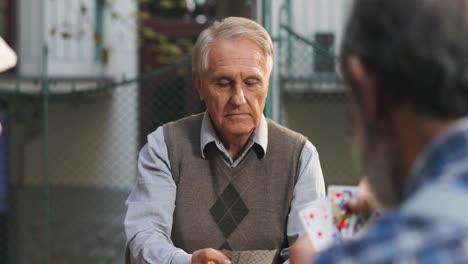 Back-View-Of-The-Senior-Retired-Man-Doing-His-Confident-Turn-In-Cards-Game-With-His-Friends