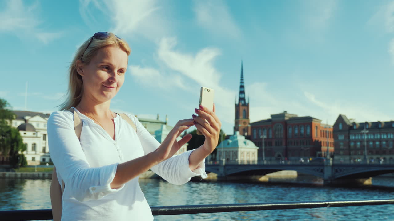 젊은 백인 여성은 도시의 아름다운 전망을 배경으로 자신의 사진을 찍습니다.