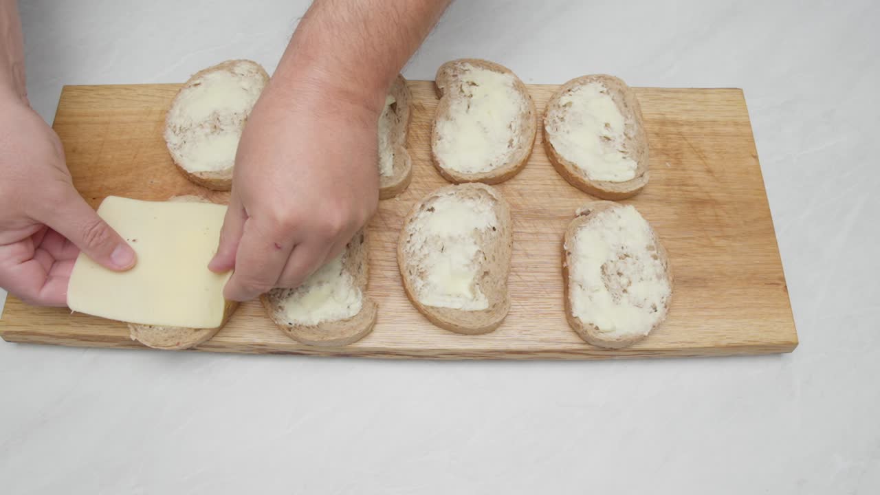 Disposizione di fette di formaggio su pane imburrato su un tagliere di legno