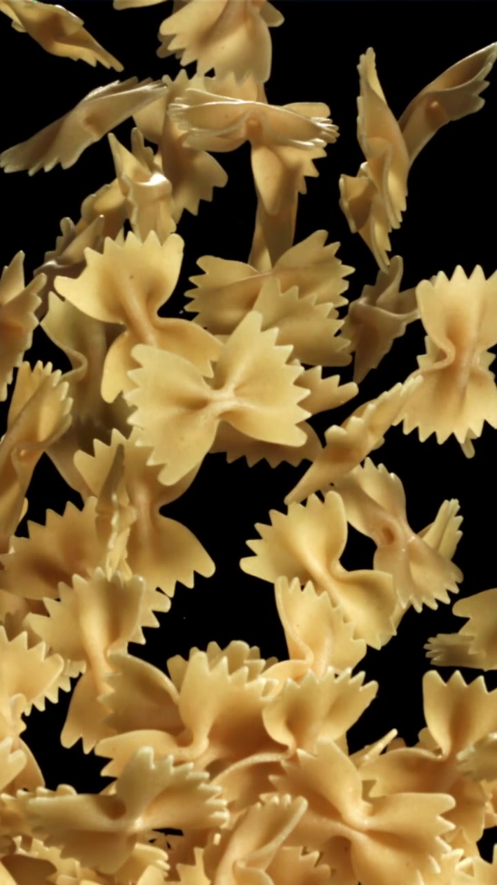 Movimento rallentato di pasta farfalle che cade su sfondo nero