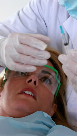 paciente aterrorizado mirando la aguja en la silla del dentista.
