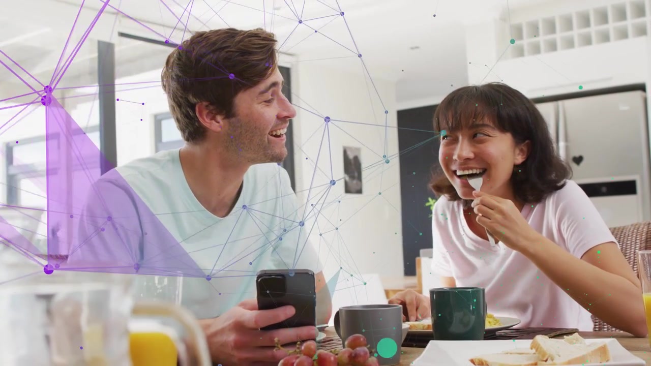 Hombre sosteniendo un teléfono, mujer comiendo con tenedor y riendo, compartiendo el desayuno, con una superposición tecnológica que conecta el teléfono.