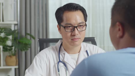 close up of asian male doctor with a fat male patient in clinic, sitting at desk, discussing about the results of medical check up, giving bad news, encouraging a patient