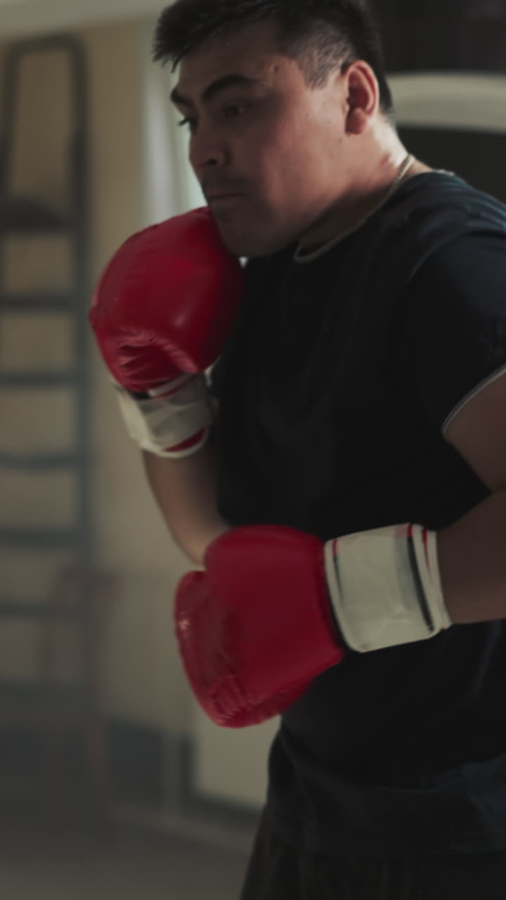 el atleta lucha con la bolsa de boxeo en un club deportivo. el deportista agresivo golpea el equipo de entrenamiento en un gimnasio vacío a cámara lenta. desarrollo de artes marciales