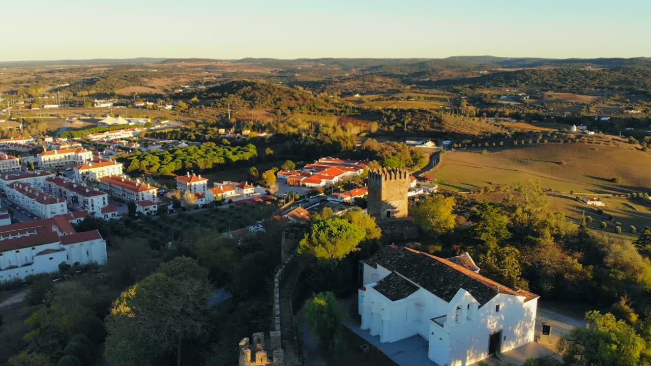 fotografía de un avión no tripulado de una capilla blanca construida en una colina con muralla y torre medieval en alentejo, portugal