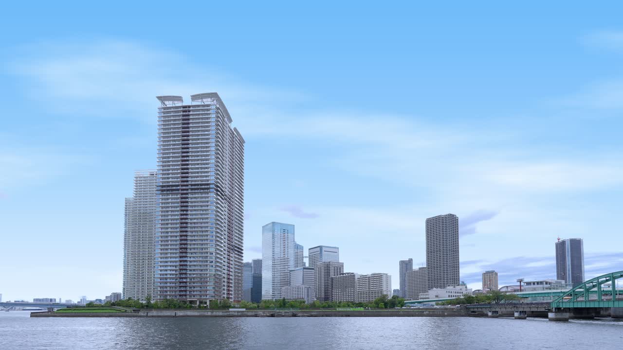 Uma foto panorâmica e tranquila do horizonte de Tóquio a partir de um calçadão à beira-mar, com edifícios modernos de vários andares e céu limpo