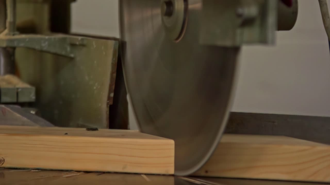 Power saw blade cutting through wood with sparks and dust during active woodworking process