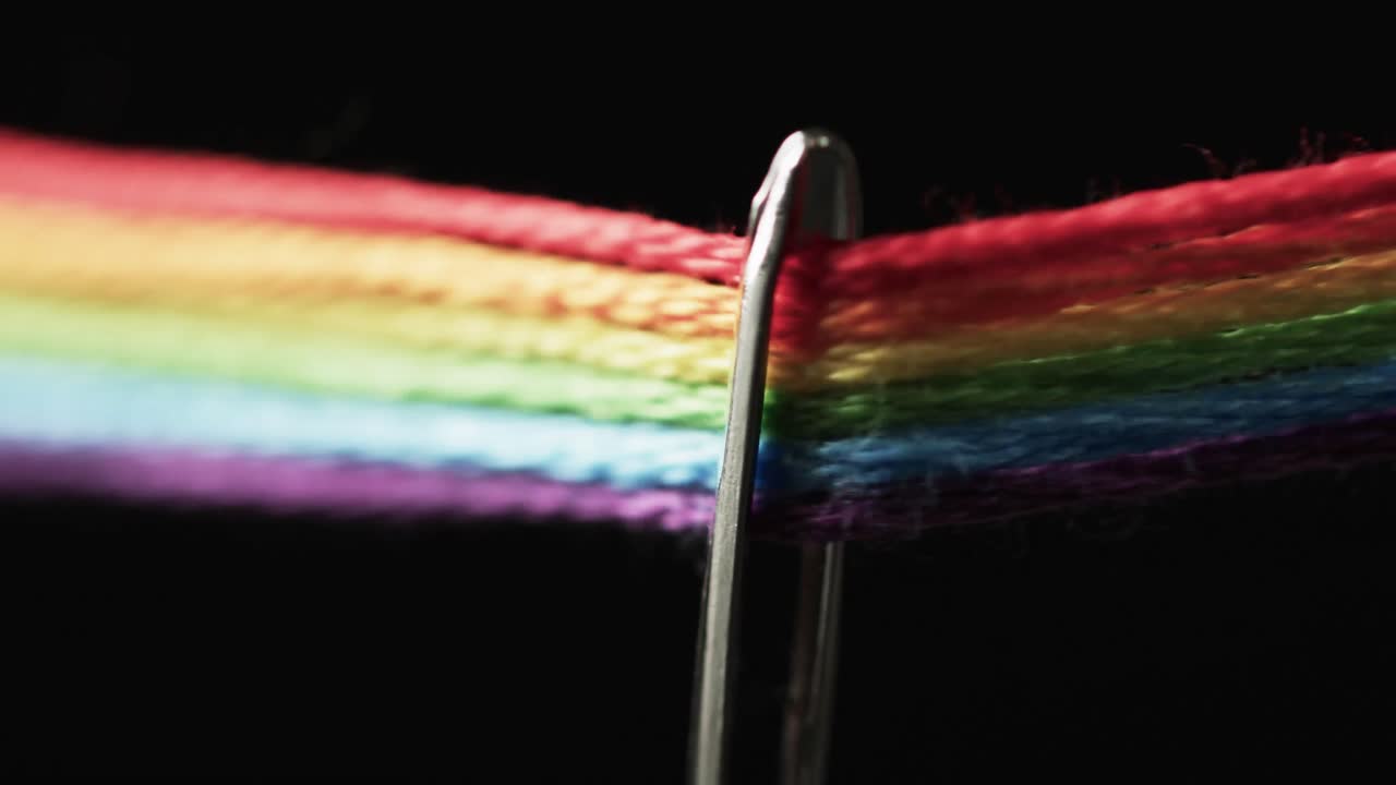 video de micro de hilos de color arco iris que pasan a través de la aguja con espacio de copia en fondo negro