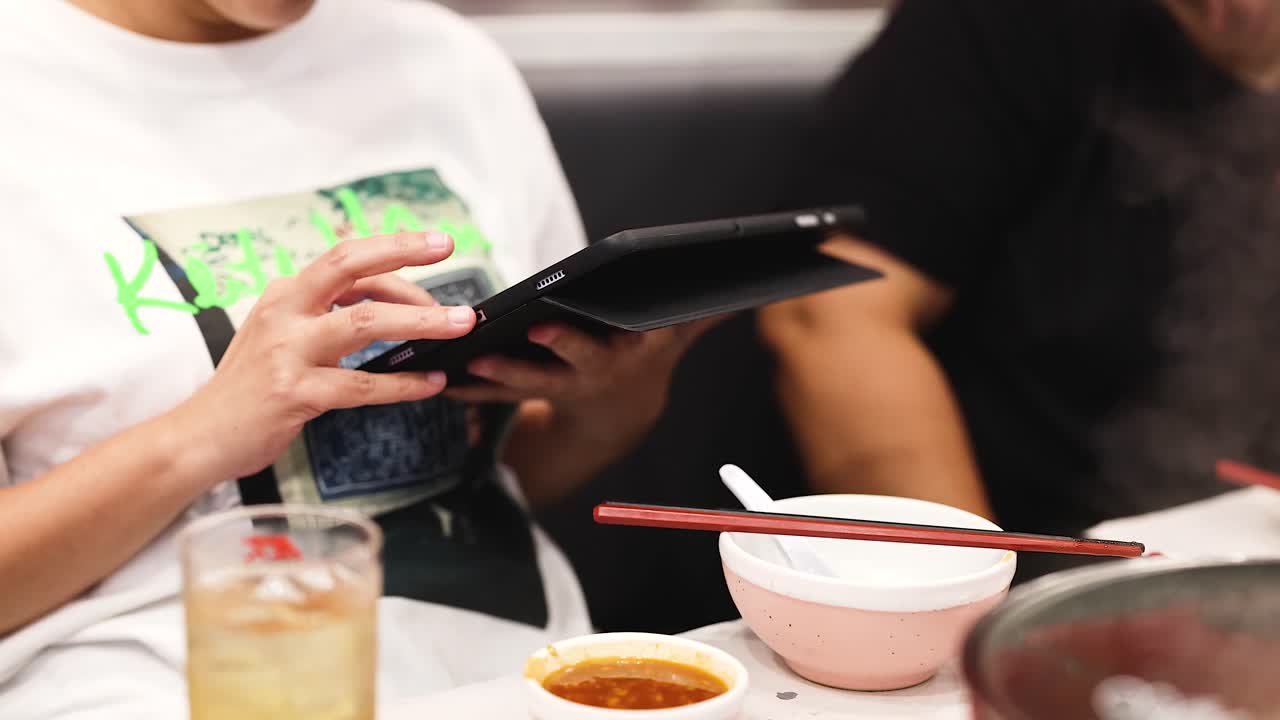 personas que usan una tableta mientras cenan juntas