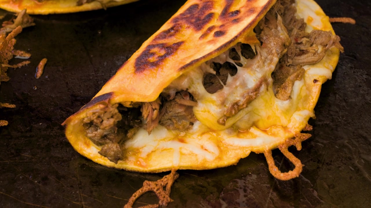 Imagens de comida mexicana mostrando close-up de taco de quesabirria cozinhando na grelha durante a preparação e o serviço de autênticos tacos de quesabirria.