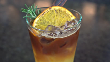 orange and lemon juice soda topped with black coffee in glass with rosemary and cinnamon