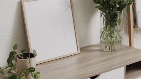 Wooden-frame-with-copy-space-on-white-background-with-plants-on-desk-against-white-wall