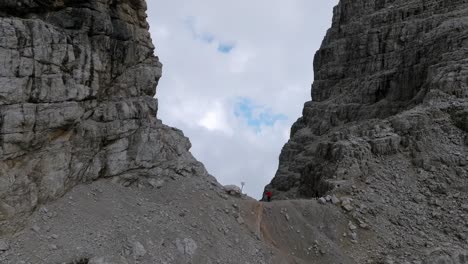 aerial establishing shot of person standing on edge of mountain and enjoying spectacular view into valley with dense clouds