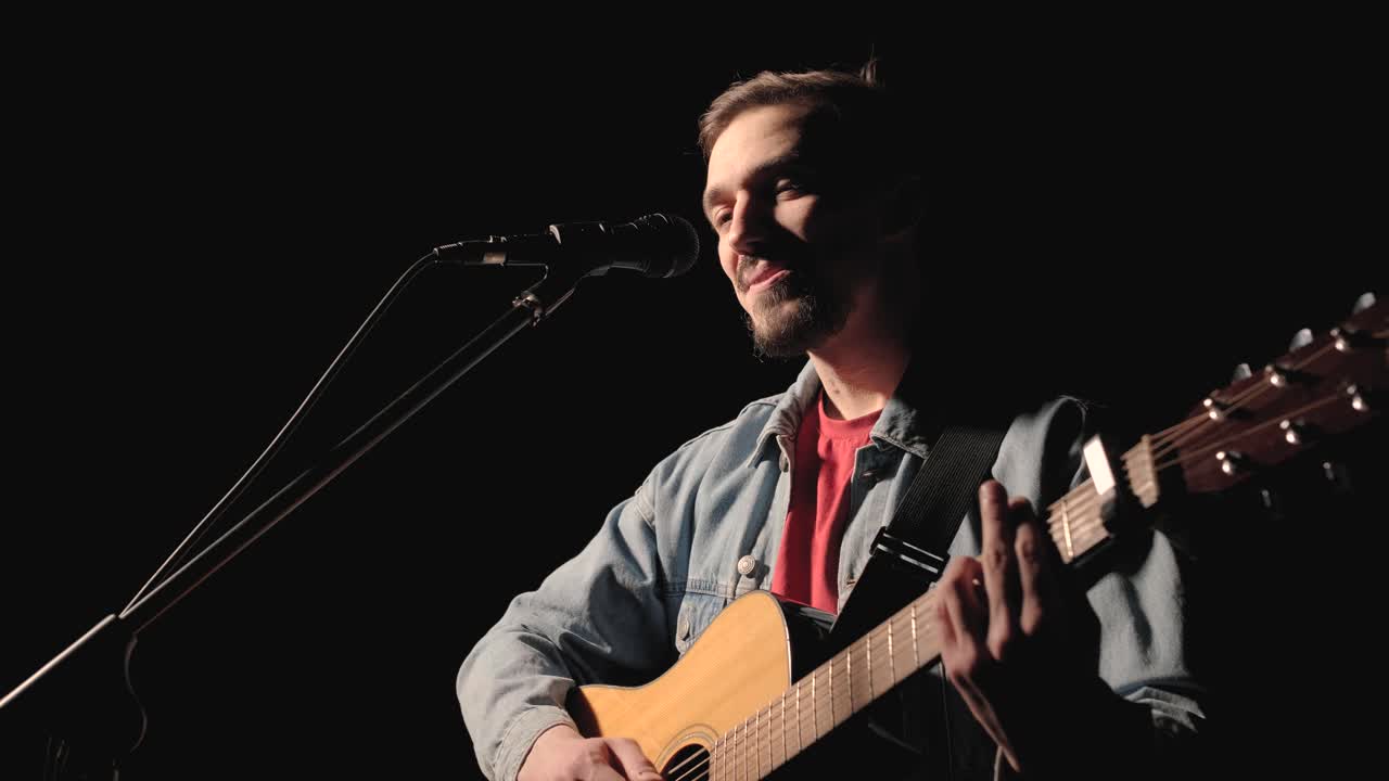 한 뮤지션이 큰 무대에서 기타를 연주하고 있으며, 관객들은 배경에 불을 들고 있습니다. 관객실은 아름다운 박이는 불빛으로 가득 차 있습니다.