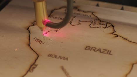 cnc laser cutting machine cuts world map on wooden plank and plywood