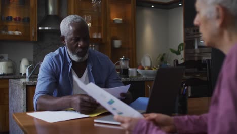 Mixed-race-senior-couple-discussing-and-calculating-finances-at-home